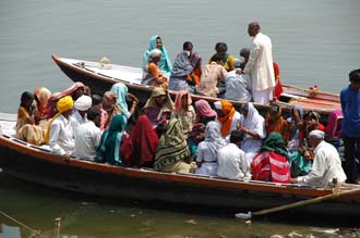 VNS Varanasi or Benares - Hindu pilgrims in colourful dress crossing the holy waters of river Ganges by boat near Harishchandra Ghat 3008x2000